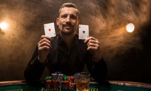 Man is playing poker with a cigar and a whiskey, a man show two cards in the hand, winning all the chips on the table with thick cigarette smoke. The concept of victory